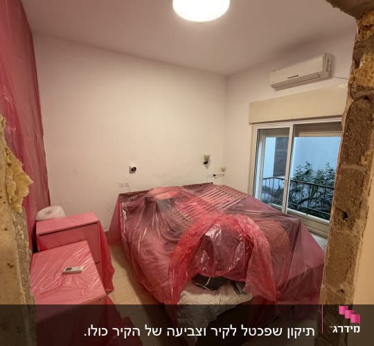 חדר עם רהיטים מכוסים בניילון לקראת צביעה